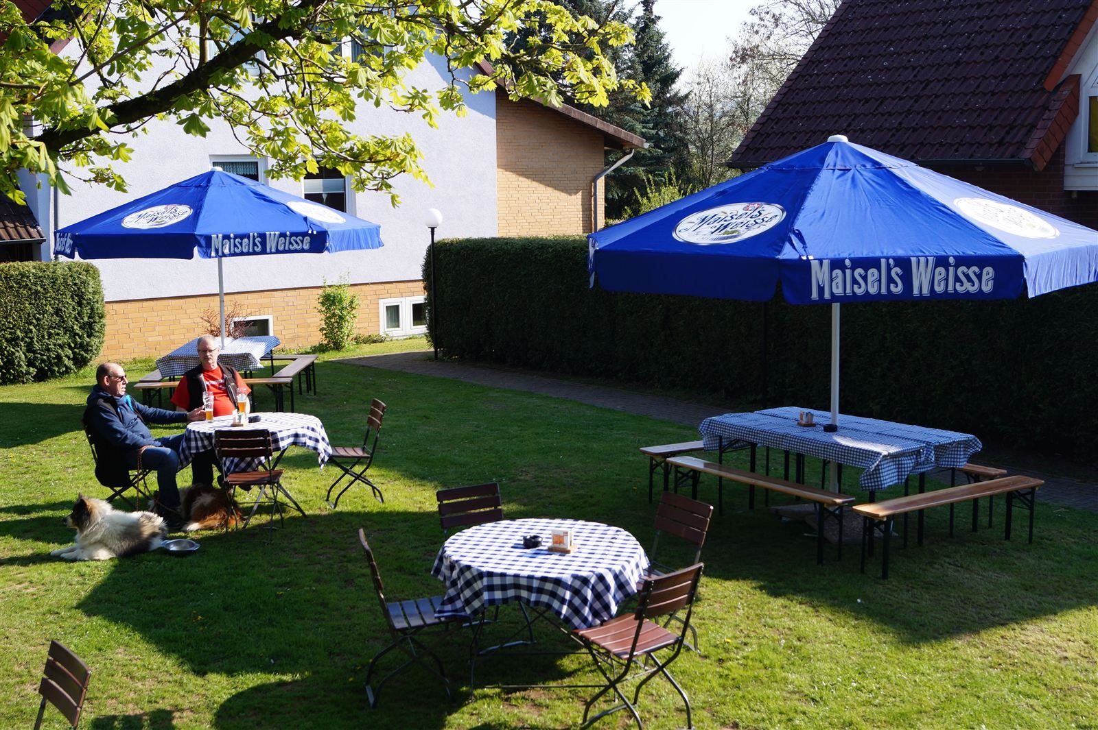 Biergarten mit Sonnenschirmen auf der Wiese am Landgasthaus
